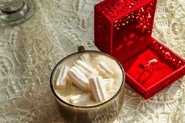 Coffee Cup with marshmallows ring in a box on the table with lace tablecloth surprise concept for woman