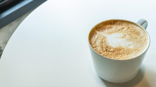 Coffee cup with milk and art shape on white table background copy space