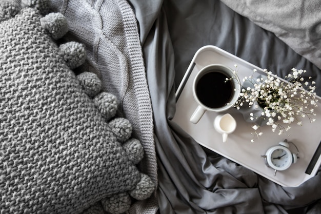 Coffee cup with milk and flowers on a tray in bed