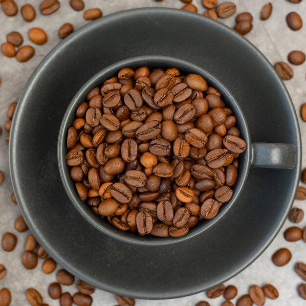 Photo coffee cup with roasted beans on stone background top view