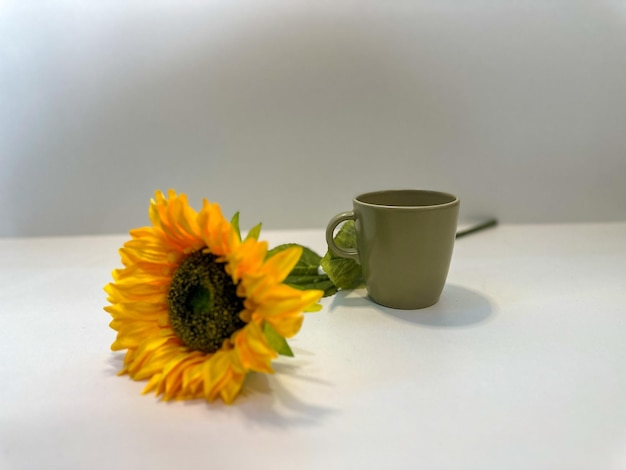 Coffee cup with sunflower on white background Creative photo