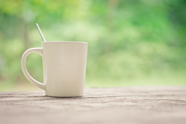 Coffee cup on wooden background textured with copy space.