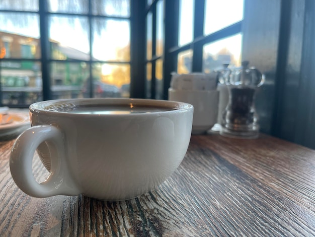 Coffee cup on wooden table at cafe with panoramic windows