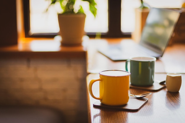 Coffee cups and laptop on table Coffee break Idyllic place for work Freelance work place