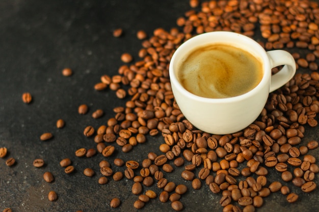 coffee drink in white cup and sprinkle coffee beans on the table