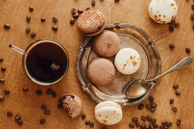 Photo coffee in glass cup and delicious macaroon cookies on vintage plate on wooden table with roasted coffee beans flat lay morning coffee and breakfast espresso with sweets