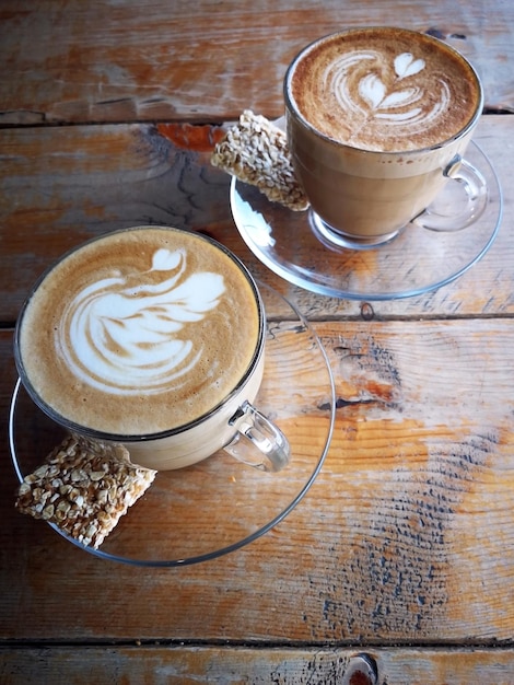 Coffee in glass cup with cookies on wooden table in cafe with lighting background