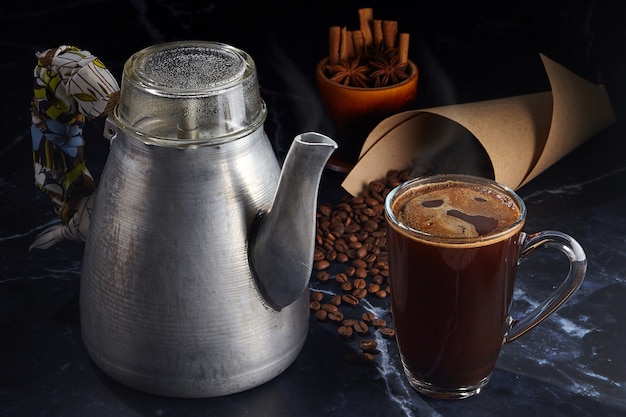 Coffee in a glass mug and a vintage aluminum geyser coffee maker