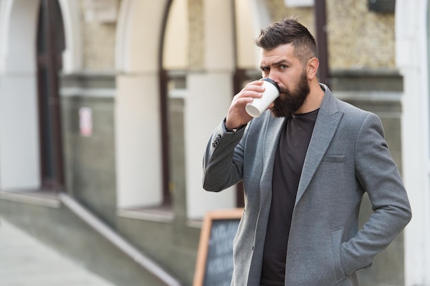 Coffee to go Hipster with disposable paper cup walking in city Bearded man drinking morning coffee Businessman in hipster style holding takeaway coffee Drinking his cup first thing in the morning