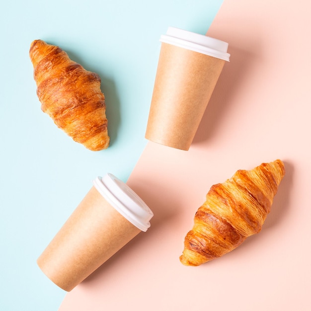 Coffee to go in a paper cup with croissants top view