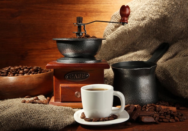 Coffee grinder turk and cup of coffee on brown wooden background