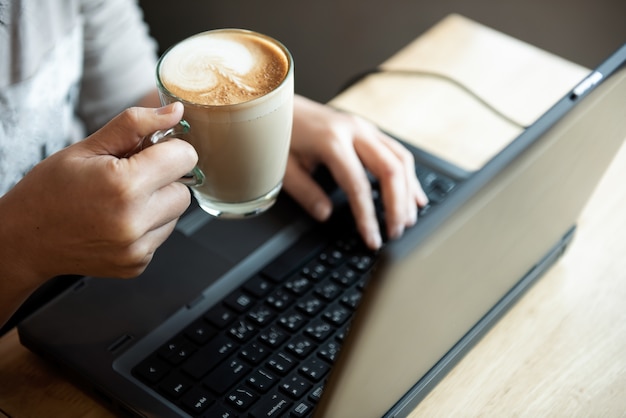 Coffee in hand office girl.She is using laptop.