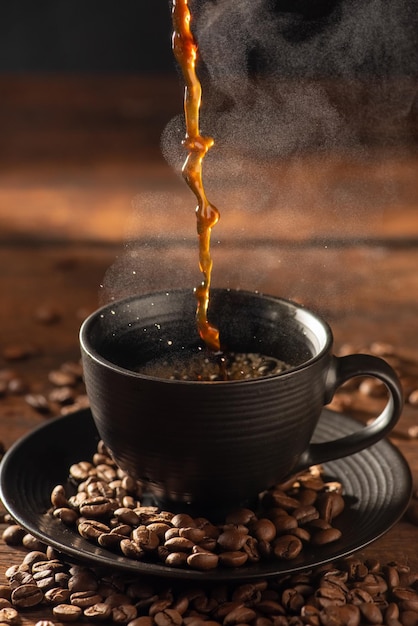 Coffee hot and Black Cup pouring coffee into a black cup on rustic wood dark food style photo selective focus