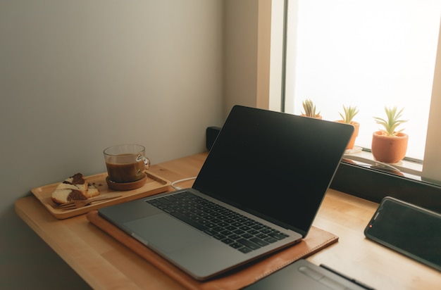 Coffee and laptop on desk in warm light.