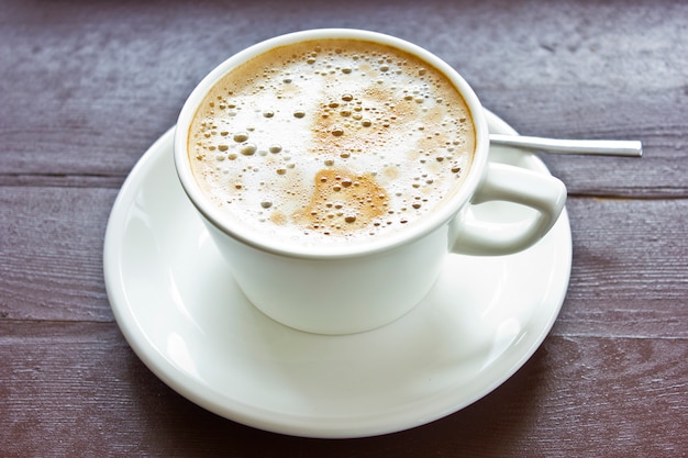 Coffee latte with milky foam and bubbles in a white porcelain cup 