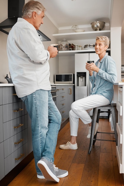 Coffee love and couple with a senior man and woman drinking coffee together in the kitchen of their home Retirement smile and morning with an elderly male and female pensioner enjoying tea