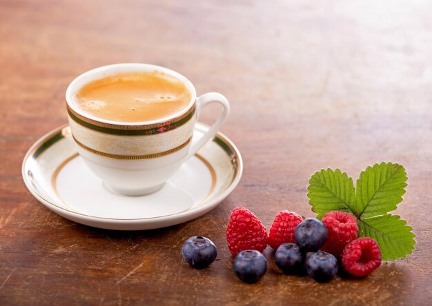 Coffee and macarons with berries on a wooden table on a wooden background