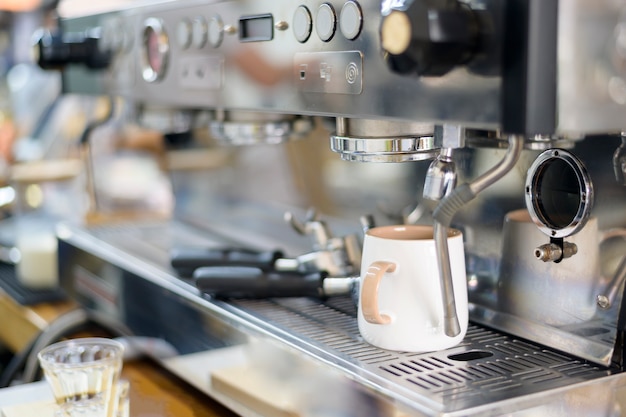 Coffee machine making black coffee and pouring into a cup at cafe