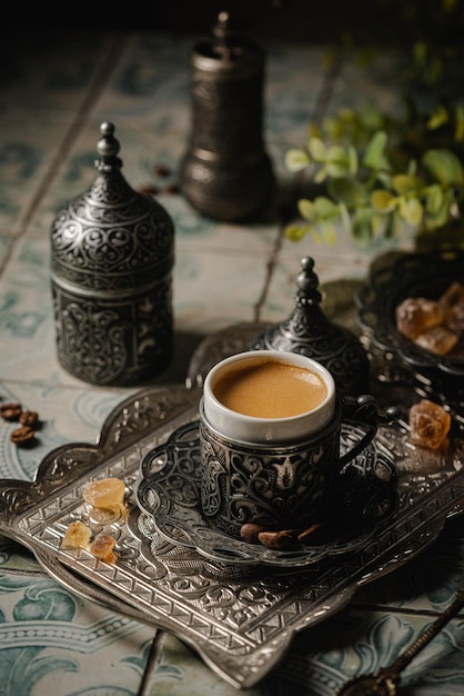 Coffee in metal turkish traditional cup and coffee beans on tile background