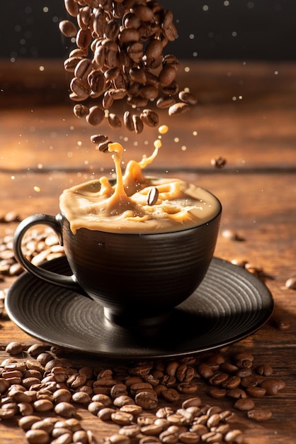 Coffee and milk pouring coffee beans into a black cup filled with milk and coffee dark food style photo selective focus