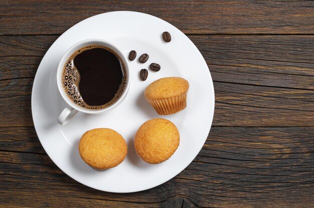 Coffee and mini muffins in plate on old wooden table, top view with copy space