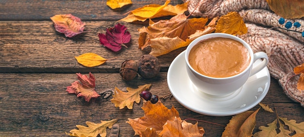 Coffee mug and autumn foliage on a wooden background Cozy autumn composition