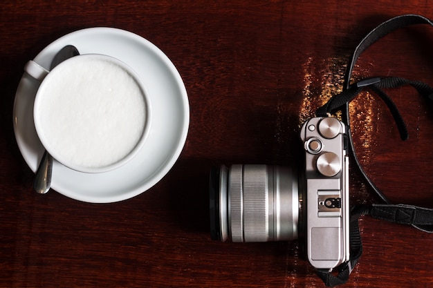 coffee mug and Vintage camera on wooden table.