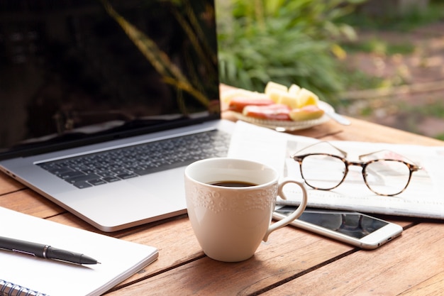 Coffee mug with laptop, glasses and newspaper Business object concept.