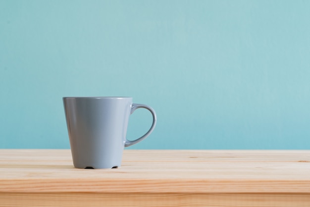 Coffee mugs place on brown wood desk and blue wallpaper