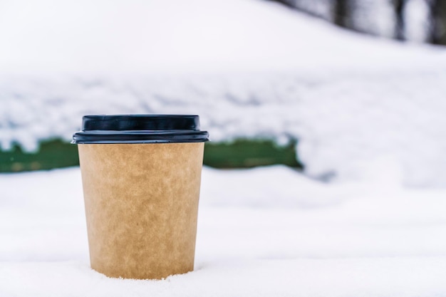 Coffee in a paper cup on a snowy winter background Hot drink in cold weather High quality photo