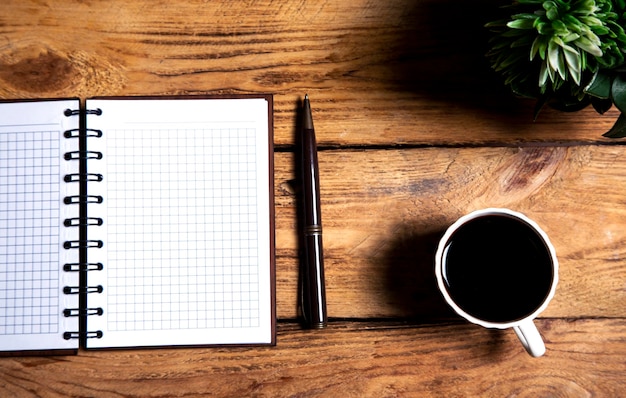 coffee pen and notebook on wooden background