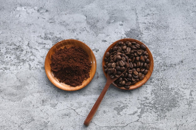 Coffee powder and beans on wooden tray and spoon isolated on gray background. 