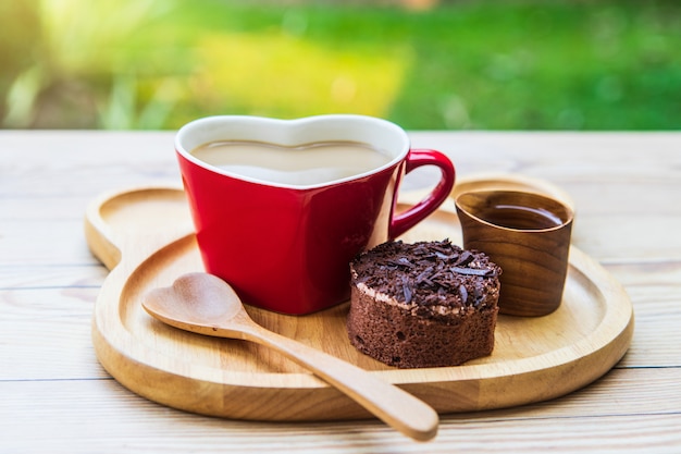 Coffee  in the red cup and chocolate cake  for breakfast in the garden.