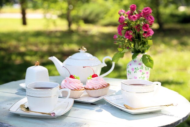 Coffee table with teacups and tasty cakes in garden