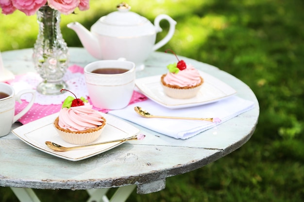 Coffee table with teacups and tasty cakes in garden