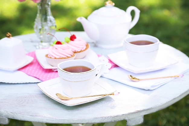 Coffee table with teacups and tasty cakes in garden