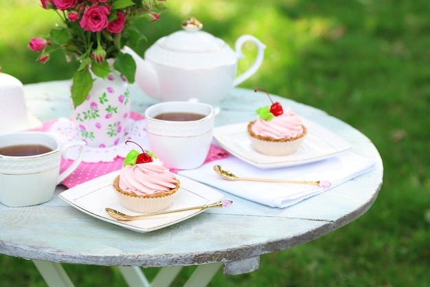 Coffee table with teacups and tasty cakes in garden