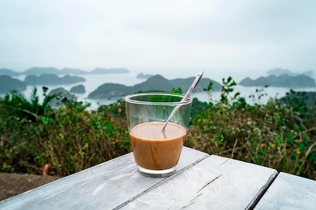 Coffee or tea on table islands and mountains Traditional Vietnamese coffee with condensed milk in a glass transparent glass on the background of beautiful landscape of Halong Bay in North of Vietnam