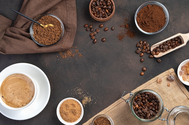 Coffee wall with a cup of coffee and different types of coffee on a brown wall. Top view, horizontal, copy space.