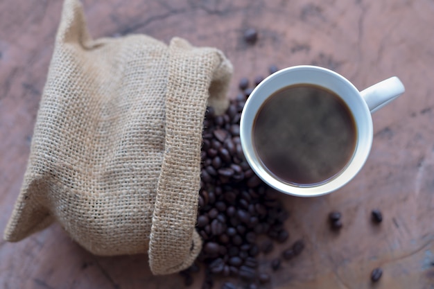 Coffee in a white cup and coffee beans on a wooden table