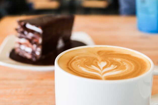 Coffee in white cup on wood table and chocolate cake background