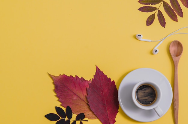 Coffee with herbarium and headphones on yellow background. Autumn. 