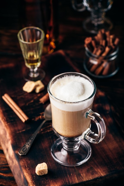 Coffee with Irish whiskey and whipped cream in glass on rustic wooden surface