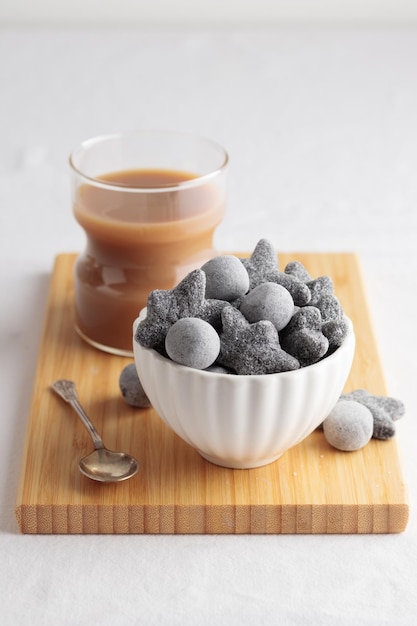 Coffee with liquorice salty salmiakki in a white bowl and a wooden cutting board