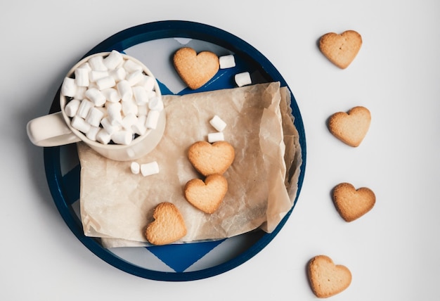 Coffee with marshmallows and heart cookies on a round blue tray Date on valentines day Nice and sweet set for Valentines day