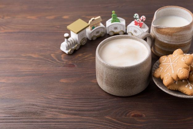 Coffee with milk and gingerbread cookies on wooden background. Winter hot drinks.