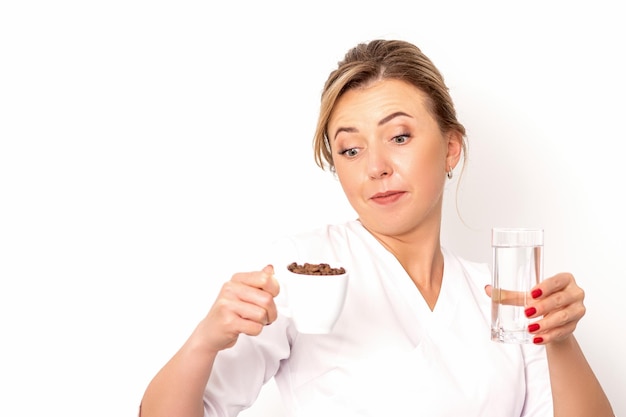 Coffee with water The female nutritionist holds a cup of coffee beans and a glass of water in her hands on white background