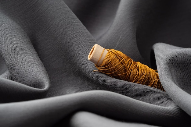 A coil with copper threads in a draped soft gray fabric closeup macro Atelier tailoring sewing background The texture of silk threads and satin fabric Fashion designer high fashion concept