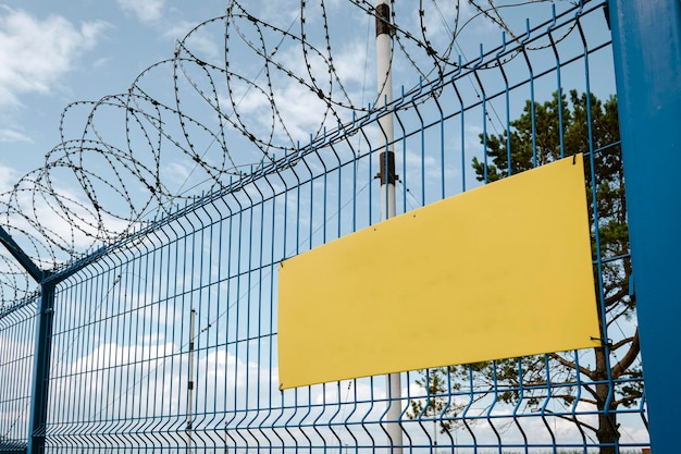 Coiled barbed wire fencing against blue sky background yellow sign on the fence wall Empty space for the text Restricted area of the airport