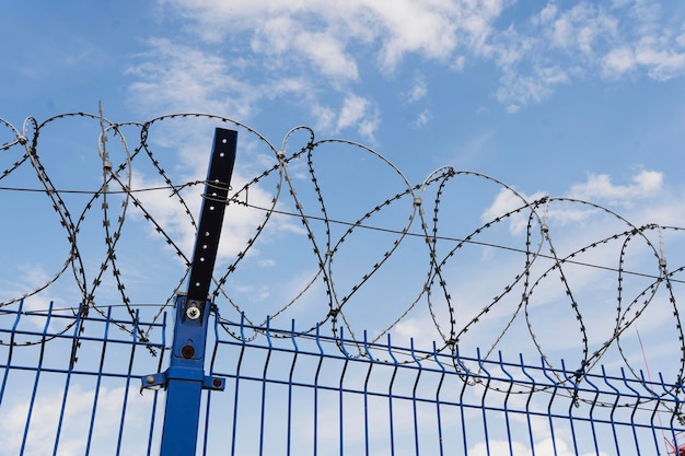 Coiled barbed wire fencing against blue sky background